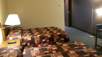 Ein Hotelzimmer mit zwei Betten, einem Nachttisch, einer Lampe und einer Stehlampe.