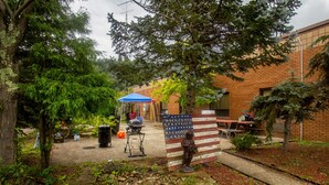 A courtyard with a statue, a barbecue grill, and a covered area. - Lafayette Inn (Moundsville)