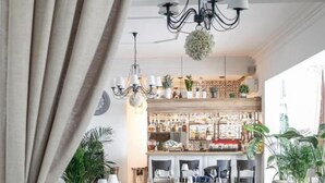 A restaurant with wooden tables and chairs, a bar area, and potted plants. - Dwór Konstancin (Konstancin-Jeziorna)