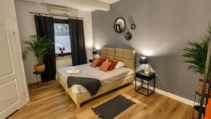 A bedroom with a bed, bedside tables, a mirror, and potted plants. - Dwór Konstancin (Konstancin-Jeziorna)