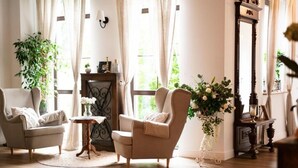 A cozy living room with two armchairs, a small round table, and a fireplace. - Dwór Konstancin (Konstancin-Jeziorna)