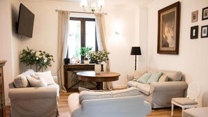A living room with two sofas, a round coffee table, and a TV mounted on the wall. - Dwór Konstancin (Konstancin-Jeziorna)