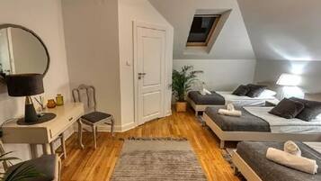 A bedroom with a desk, two beds, a skylight, and a small window.