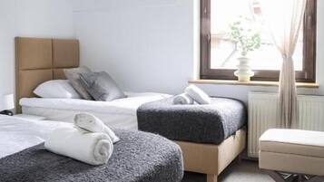 Une chambre d’hôtel avec deux lits, une fenêtre avec des rideaux, un radiateur et une petite table.