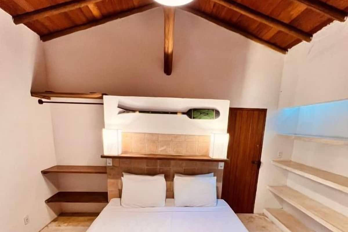 A bedroom with a bunk bed, a wooden ceiling, and a bedside table with a lamp.