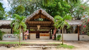 A thatched-roof structure with a sign reading "Pousada MyM Dunas".