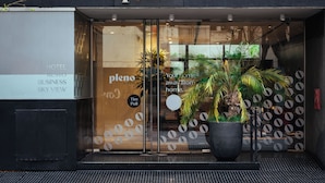 Entrada de hotel con un cartel que dice 'pleno', un cartel de 'Tire Pull' y una gran planta en maceta al frente.