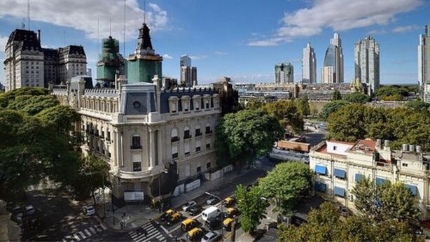 Un paisaje urbano con edificios históricos, rascacielos modernos y un cielo despejado.