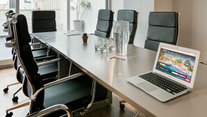 A conference room with a long table, black chairs, a laptop, and a potted plant. - Pleno Madero (Buenos Aires)