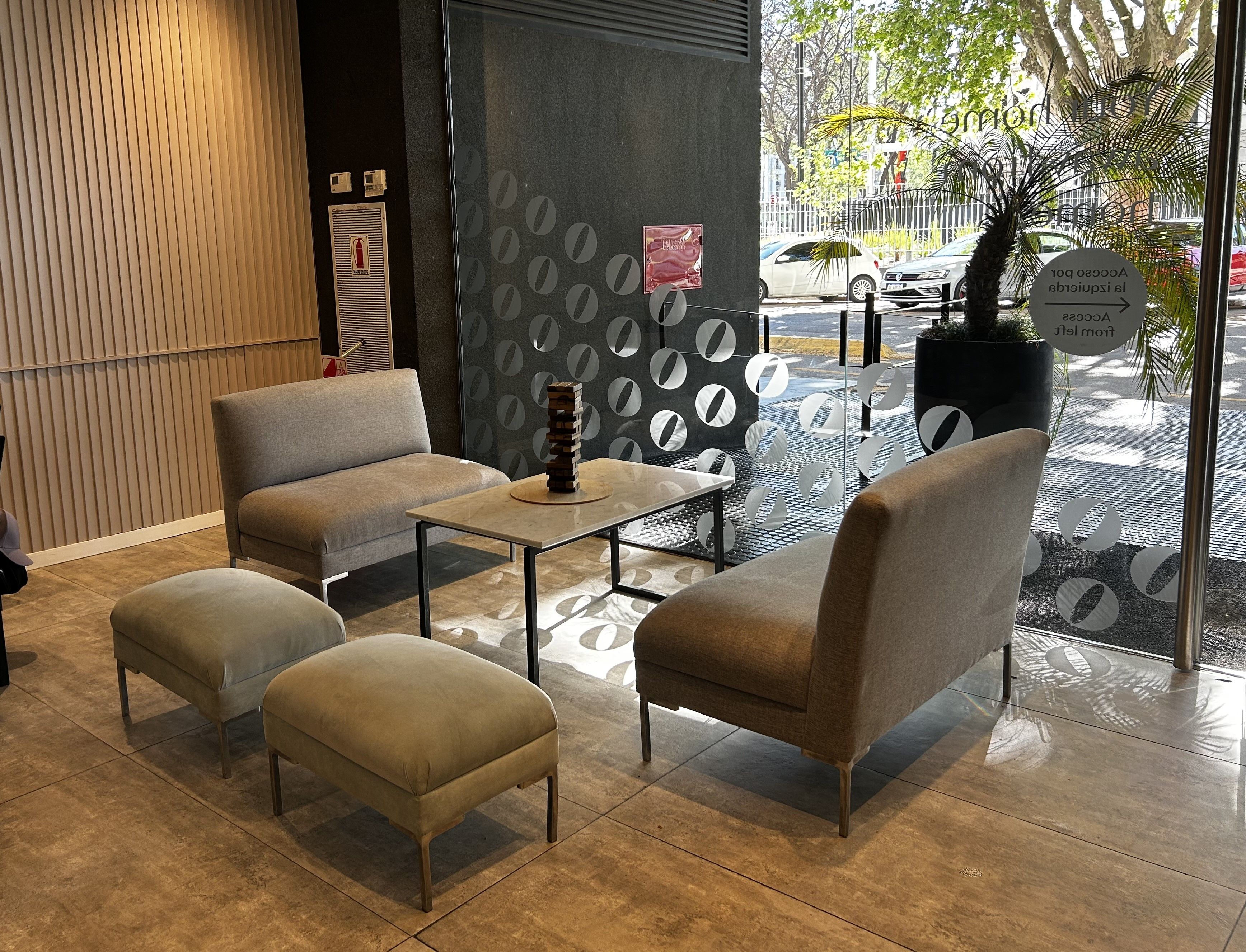 A modern interior with a sofa, ottoman, and a table with a decorative stack.