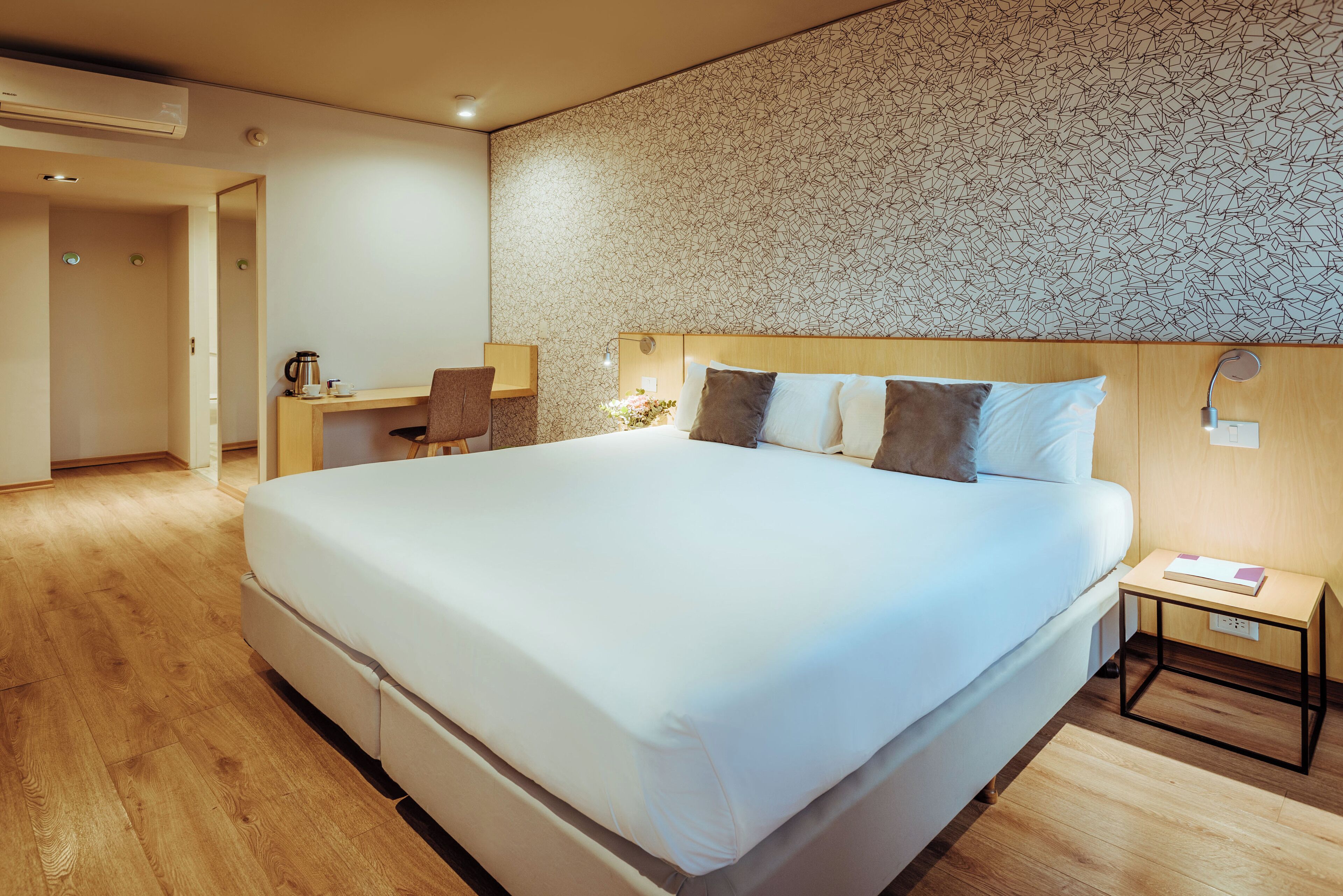 A modern hotel room with a large bed, a desk, and a chair.