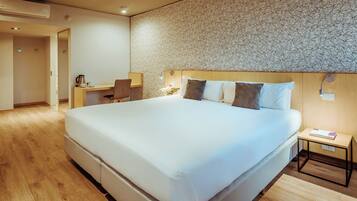 A modern hotel room with a large bed, a desk, and a chair.