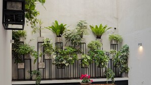 Un patio con una mesa de madera y bancos, rodeado de diversos maceteros y un jardín vertical en la pared.