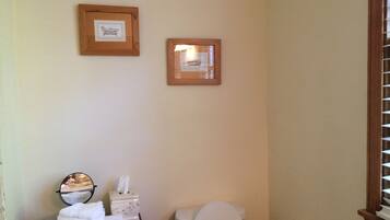 Une salle de bain avec des toilettes, une boîte de mouchoirs et une serviette posée sur le comptoir. Deux tableaux encadrés sont accrochés au mur.