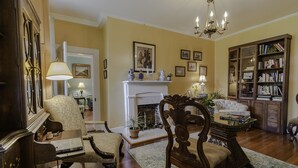 A traditional living room with a fireplace, a bookshelf, and a chandelier.