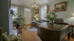 A spacious living room with a wooden coffee table, a sofa, and a dining table. There are potted plants and a chandelier.