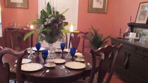 A dining room with a round table set for six, surrounded by wooden chairs.