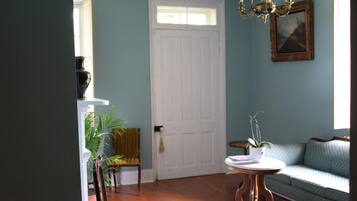 A room with a white door, a chandelier, a sofa, and a small table with a plant.