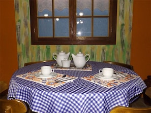 A round table with a blue and white checkered tablecloth, white teapots, cups, and a tray with cutlery. - Pousada Colina Verde (Garopaba)