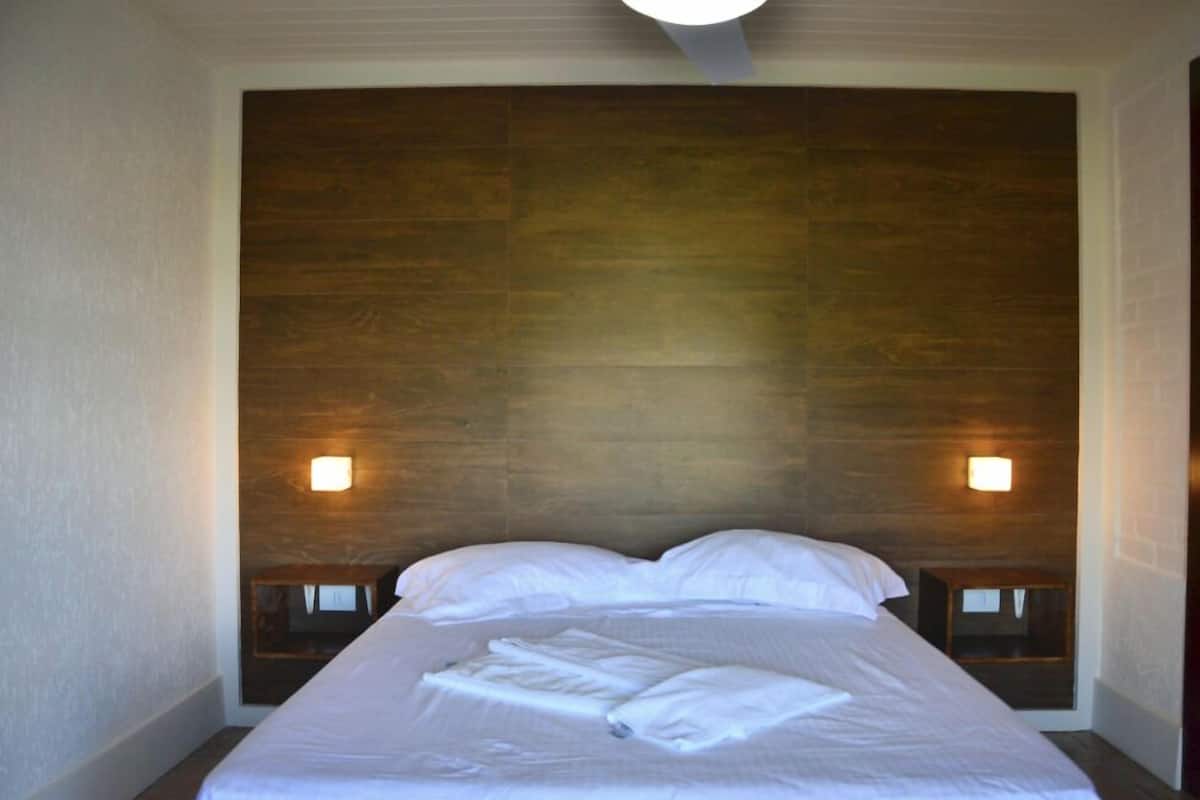 A hotel room with a large bed, two bedside tables, and a wooden headboard.