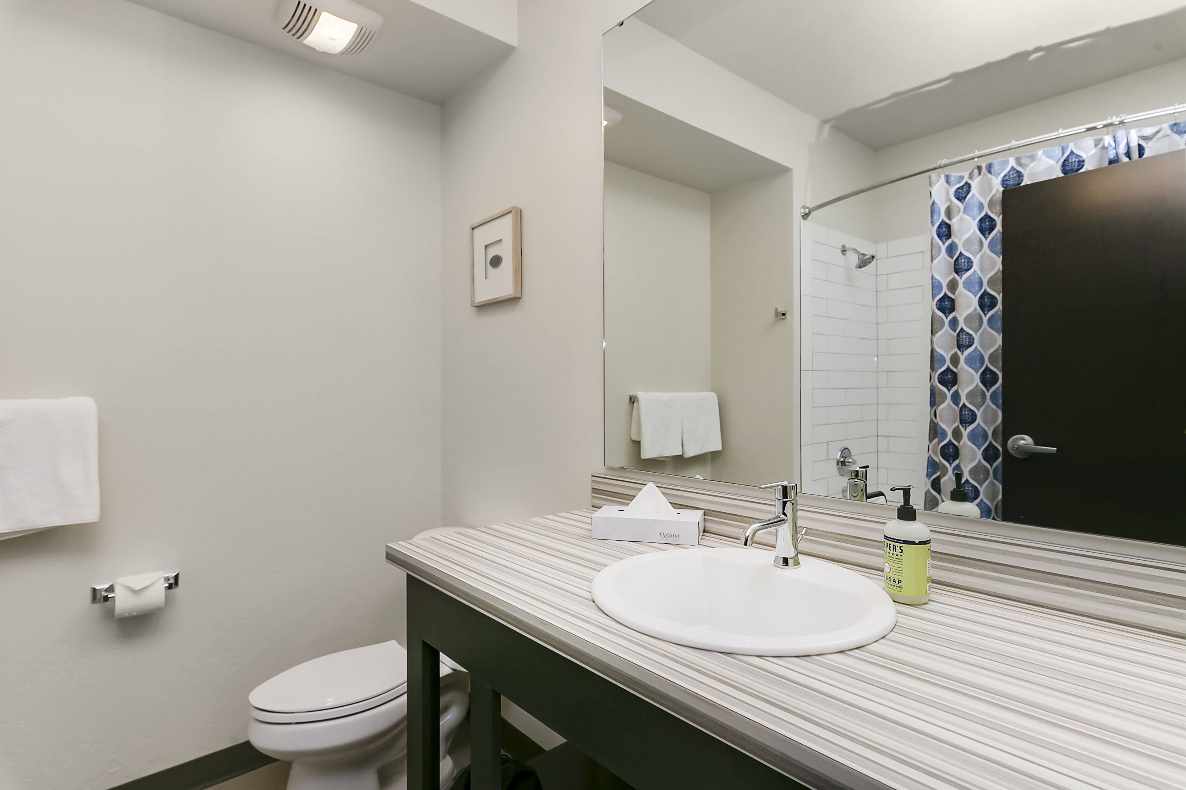 Une salle de bain avec un lavabo blanc, un miroir, un porte-serviettes et des toilettes.