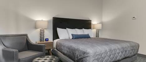 Ein Hotelzimmer mit einem großen Bett, einem Sessel, einem kleinen Tisch und zwei Lampen.