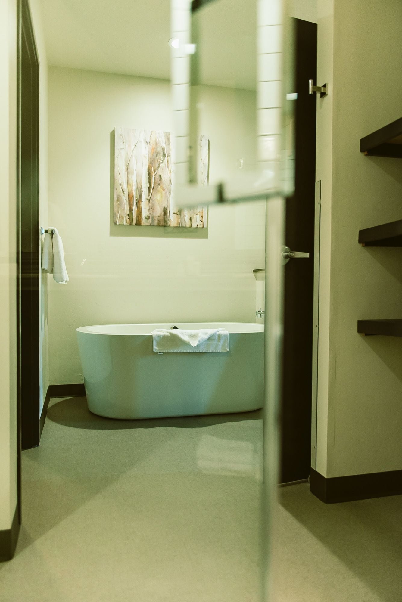 A bathroom with a bathtub, a towel rack, and a wall-mounted artwork.