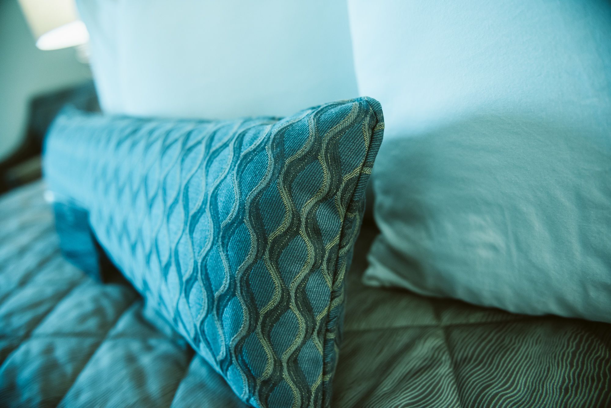 Una cama con un cojín estampado y un cojín liso.