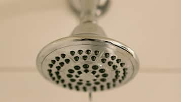 A showerhead with a round, perforated design, mounted on a wall with a grid pattern.