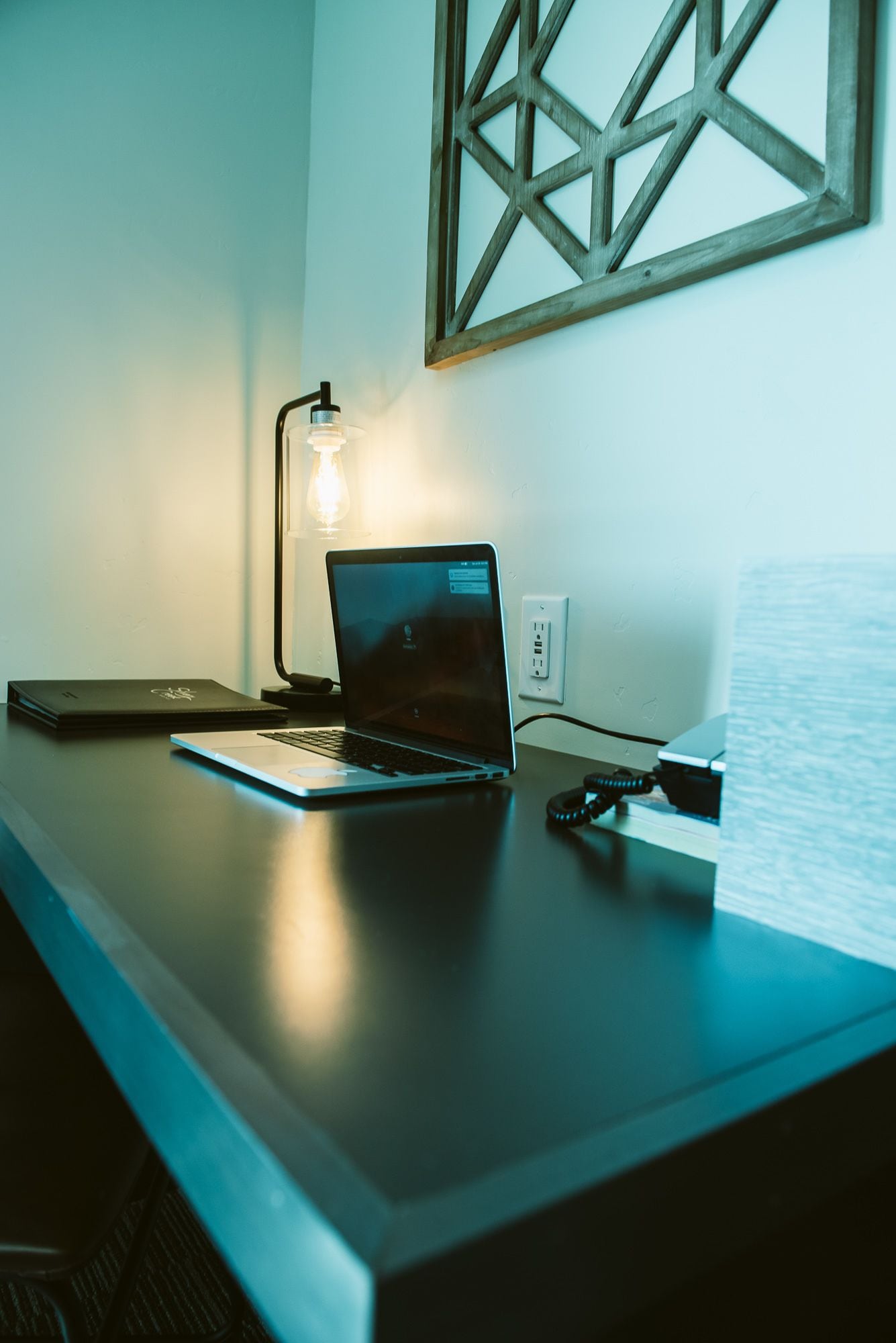 Un bureau avec un ordinateur portable, une lampe et un carnet.