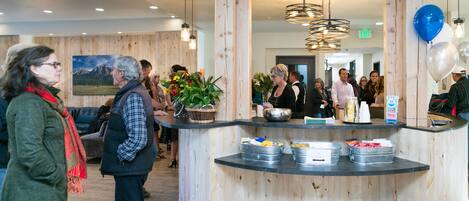A reception area with a wooden counter, metal bins, and a hanging plant.