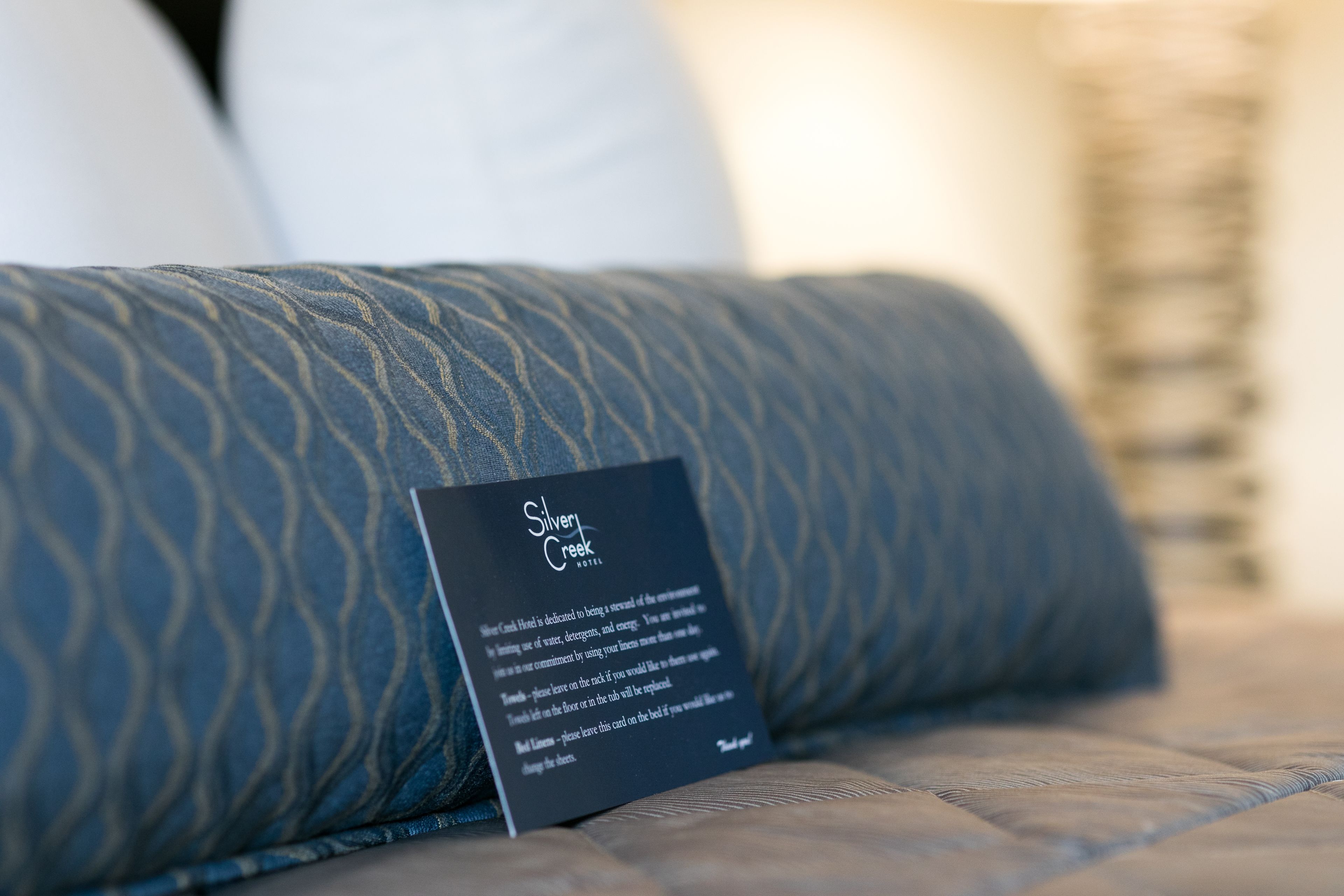 Un coussin recouvert d’un tissu bleu foncé à motifs et une carte avec du texte.
