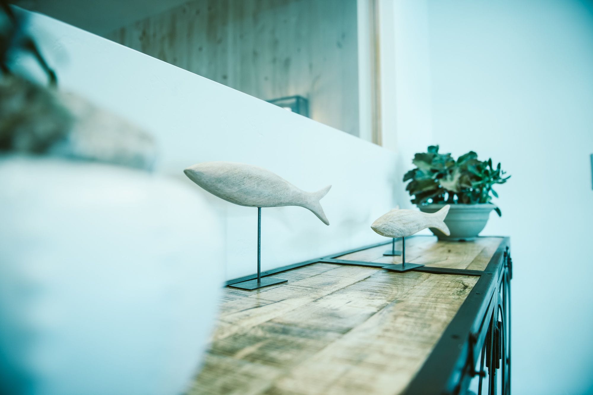 A wooden counter with two fish sculptures and a potted plant.