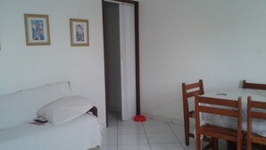 A room with a white sofa, a dining table with chairs, and two framed artworks on the wall. - Férias na Beira da Praia em Cabo Frio (Cabo Frio)