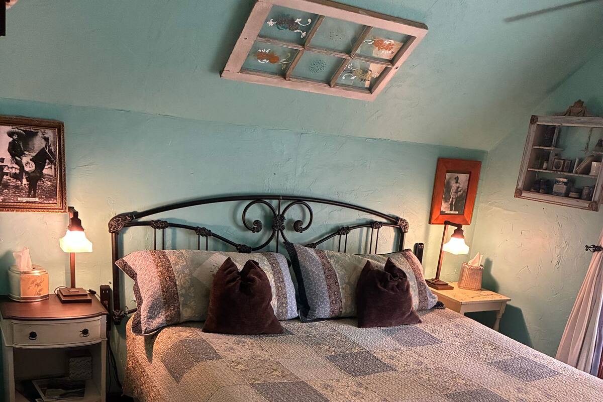 Un dormitorio con cama, mesitas de noche, alfombra y adornos en la pared.