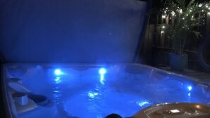 A hot tub with blue lighting, surrounded by a dark environment.