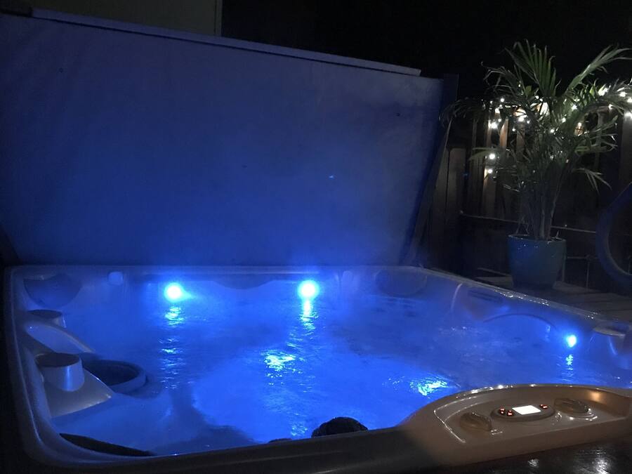 A hot tub with blue lighting, surrounded by a dark environment.