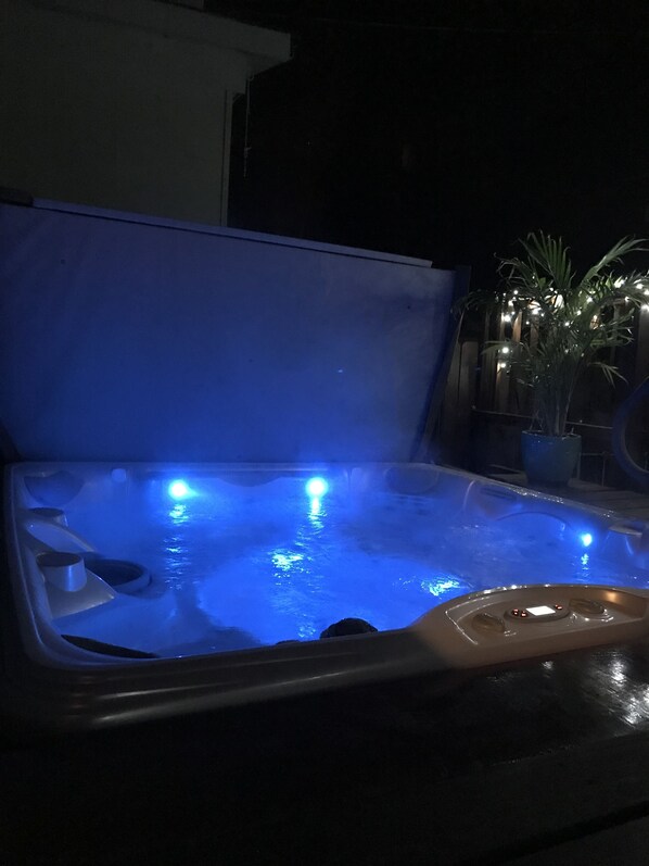 Un jacuzzi con iluminación azul, rodeado de un ambiente oscuro.