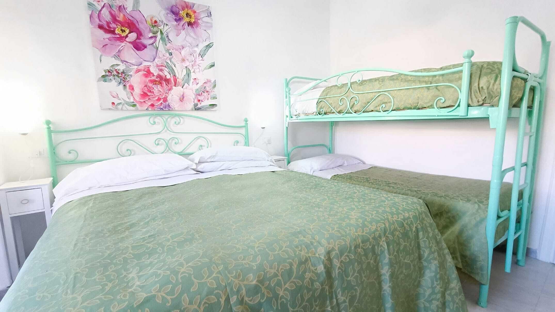 Une chambre avec deux lits superposés, une table de chevet et un tableau au mur.