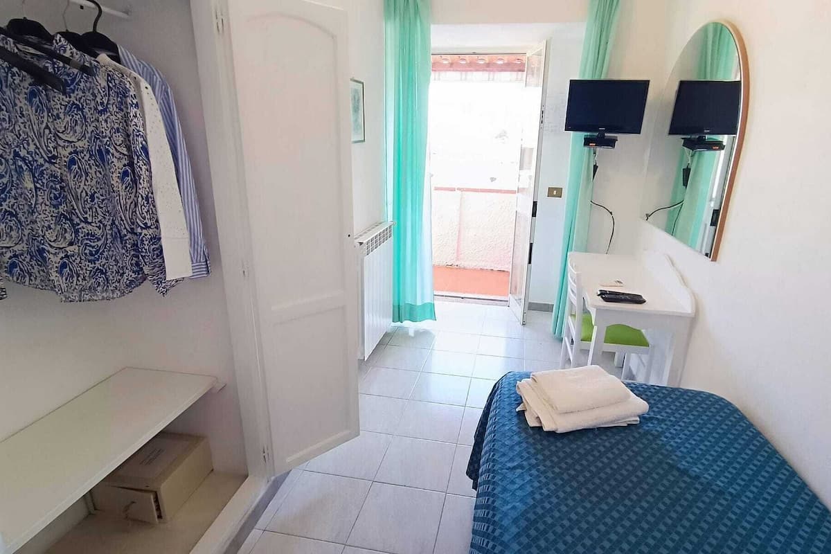 Een slaapkamer met een bed, een bureau, een stoel, een televisie en een kledingkast.