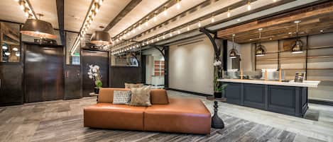 A modern interior with a leather sofa, pendant lighting, and a kitchen area.