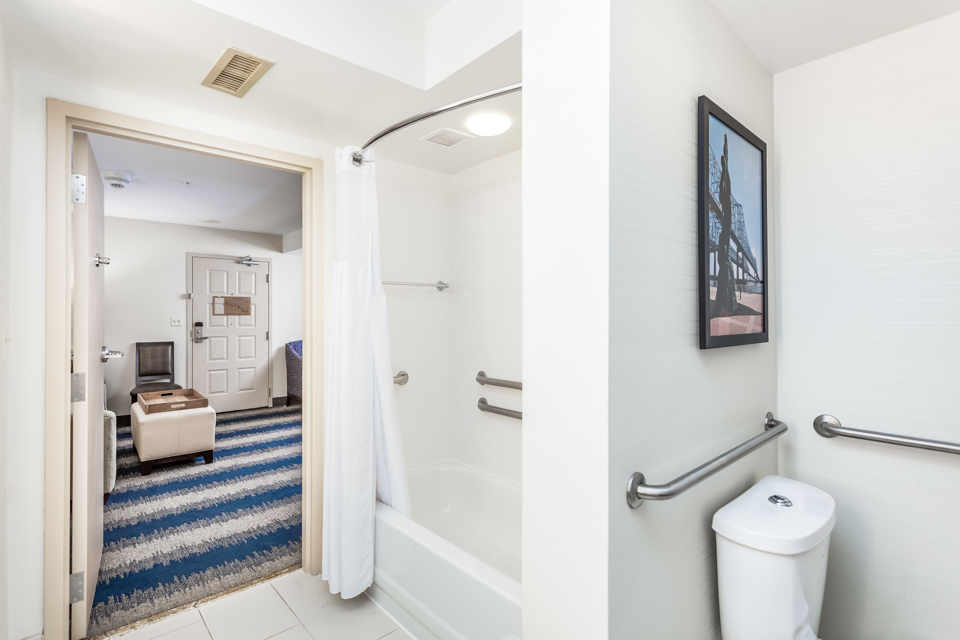 A bathroom with a shower, toilet, and a framed picture on the wall.