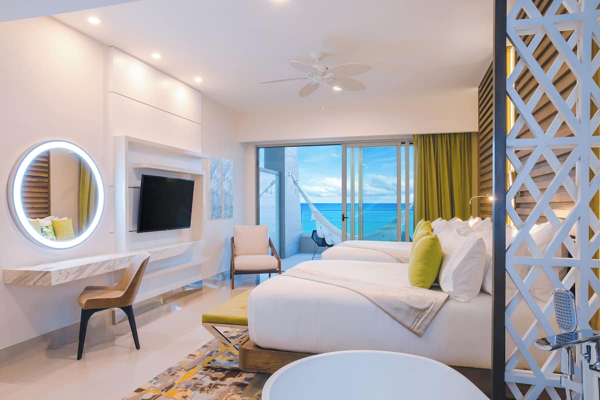 Een moderne hotelkamer met een groot bed, een bureau met televisie, een stoel en uitzicht op de oceaan.