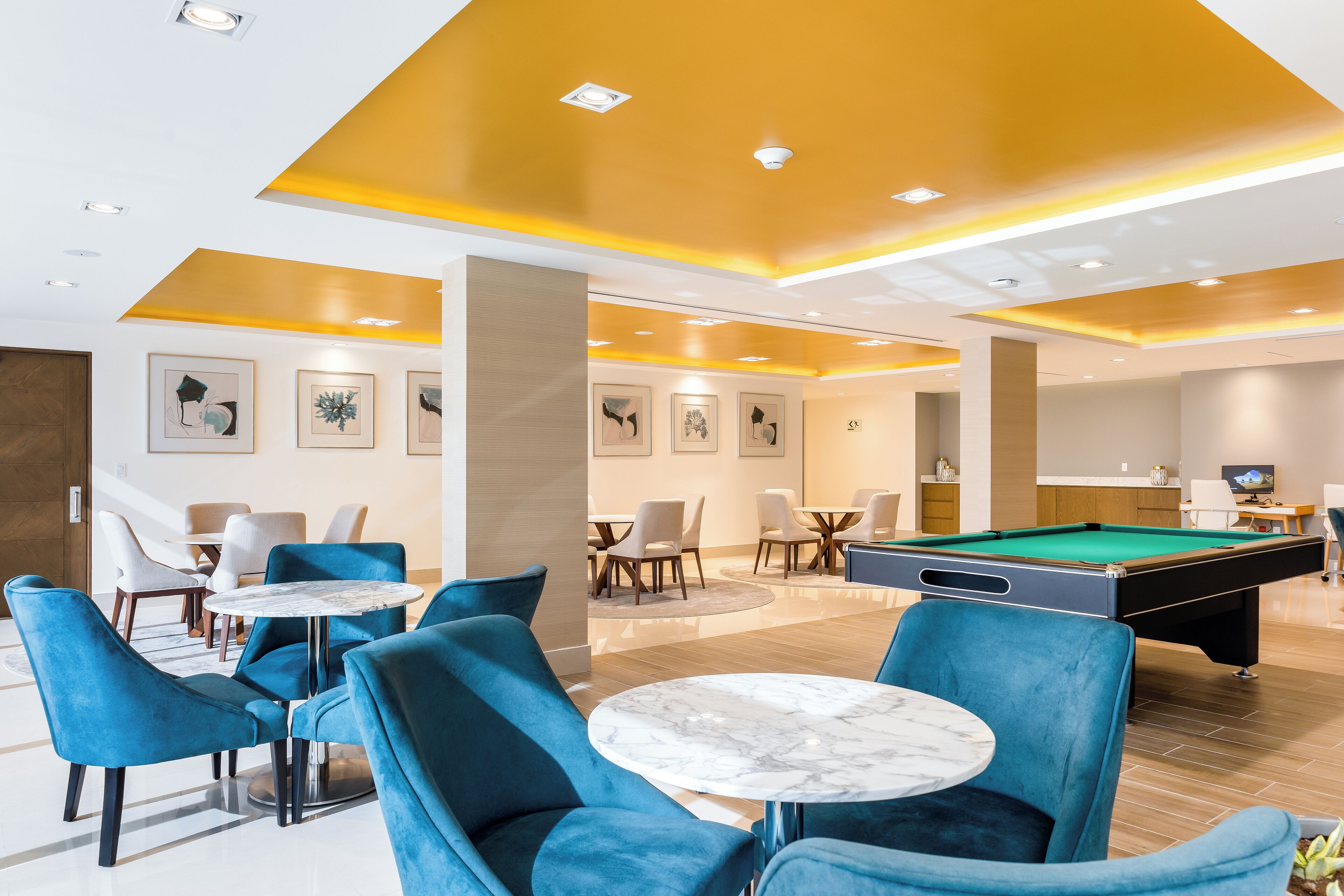 Un espacio interior moderno con mesa de billar, sillas azules y mesa de futbolín.