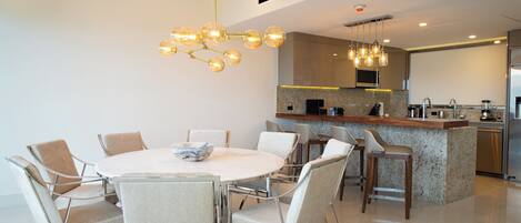 Una cocina moderna con una isla central, electrodomésticos de acero inoxidable y una lámpara colgante.