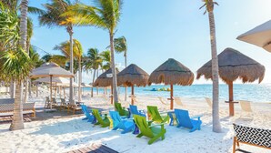 A beachside resort with thatched umbrellas, wooden deck, and colorful lounge chairs.
