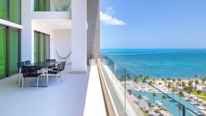 A balcony with a view of the ocean and a pool area.