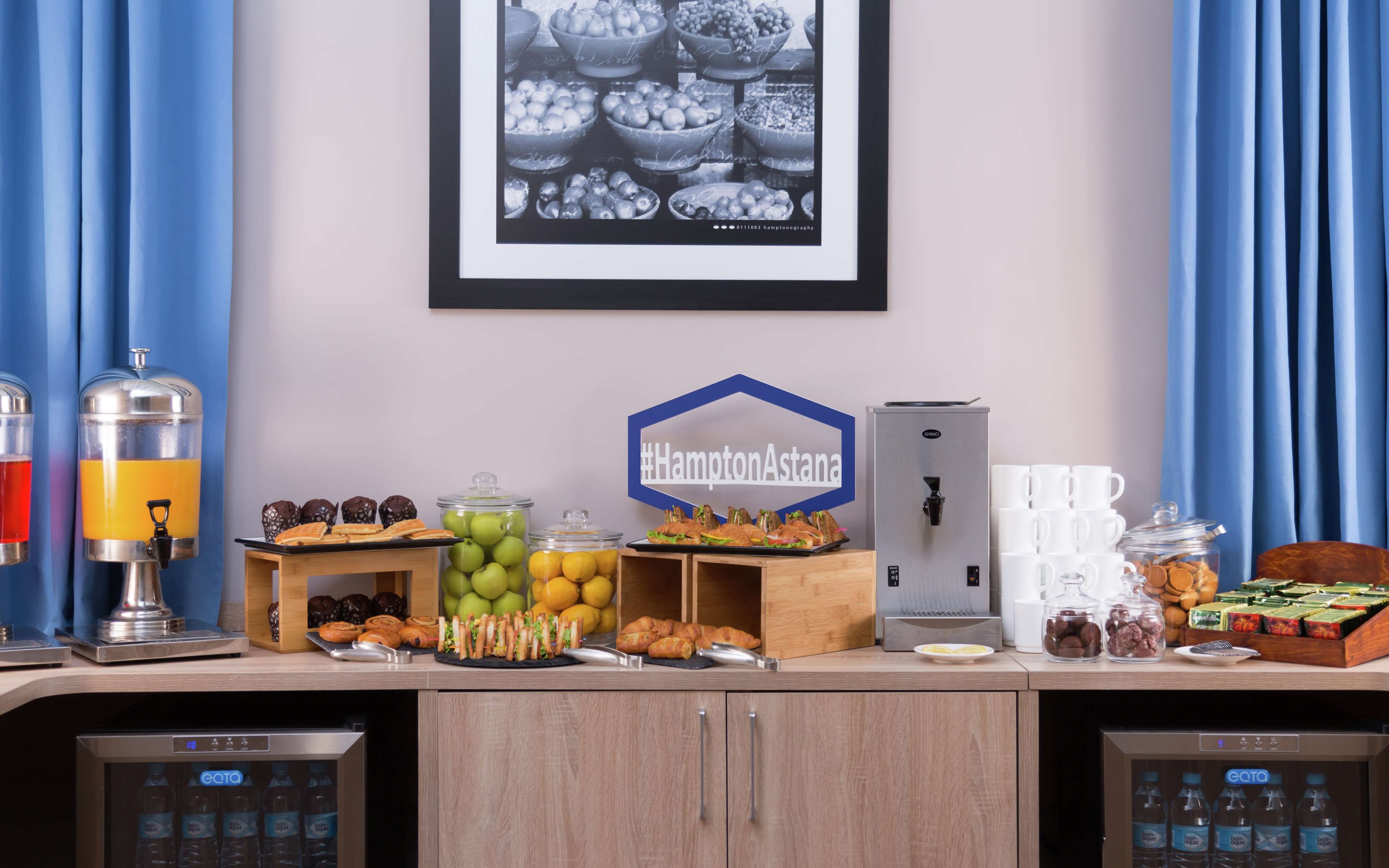 Montaje de un bufé de desayuno con diversos alimentos, una máquina de café y dispensadores de bebidas.