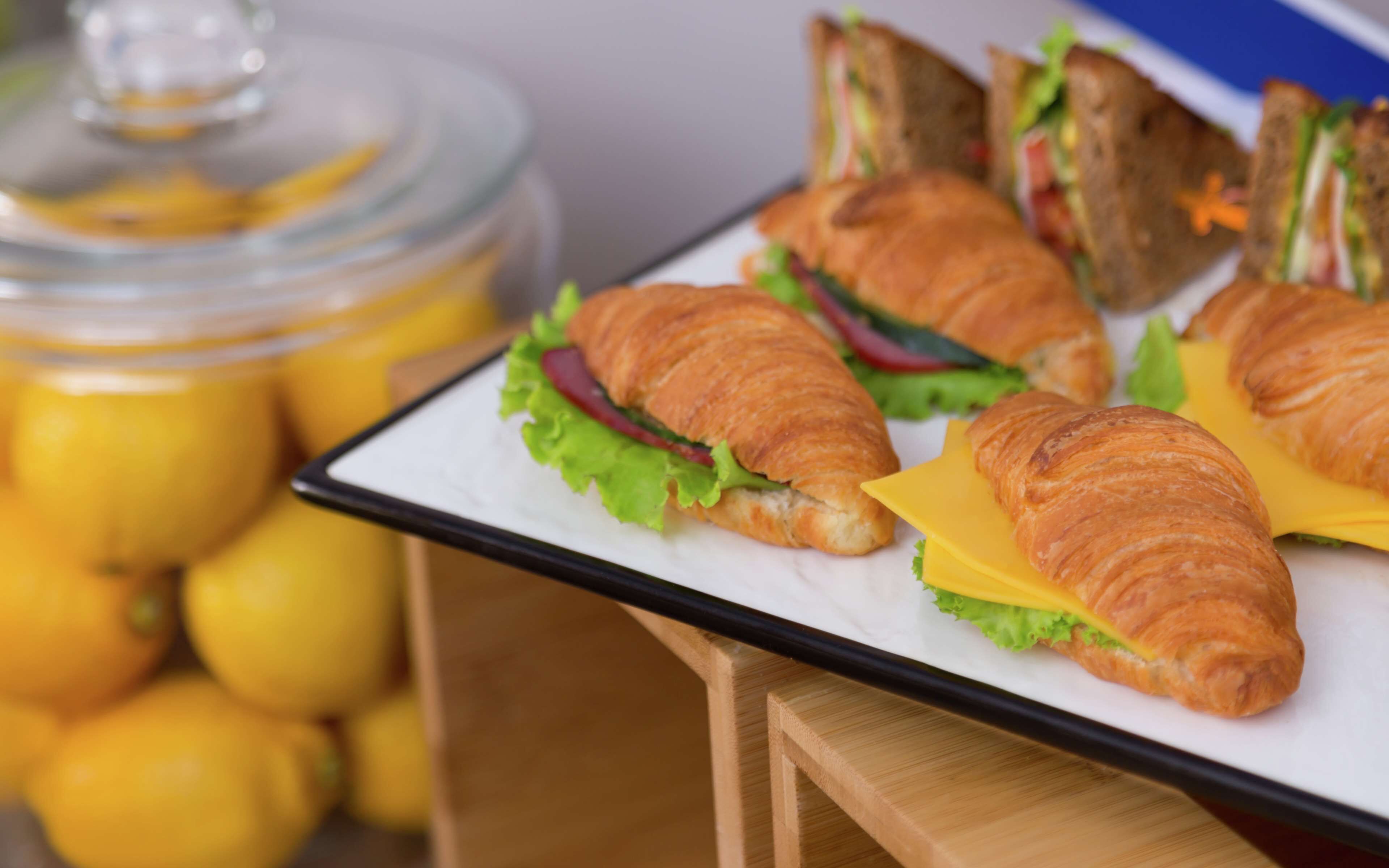 A tray of sandwiches and croissants on a table.