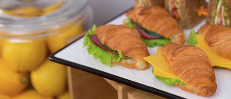 A tray of sandwiches and croissants on a table.